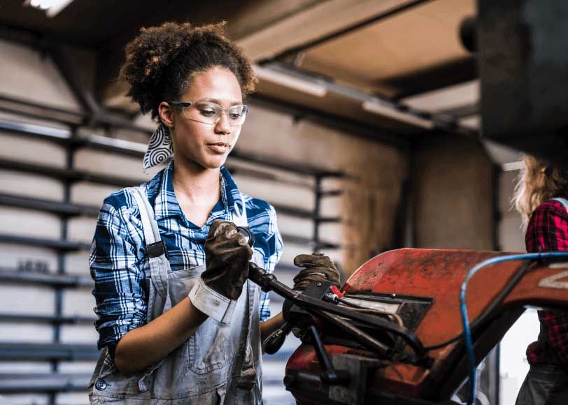 Female business owner withing with metal in her workshop